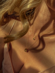 woman with blond curled hair wearing two 18 karat gold plated dainty necklaces of contrasting length