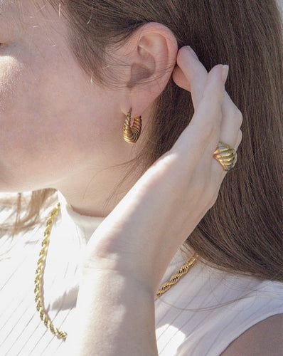 woman wearing 18 karat gold plated hoop earrings, a chunky statement ring and a rope chain
