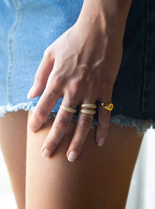woman wearing three 18 karat gold plated silver rings decorated with cubic zirconia stones and one gold signet ring