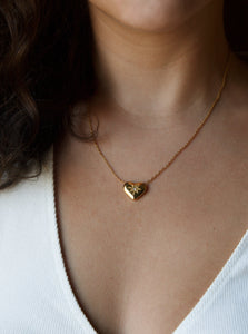 Women wearing gold plated heart-shaped pendant necklace with cubic zirconia stone in the middle